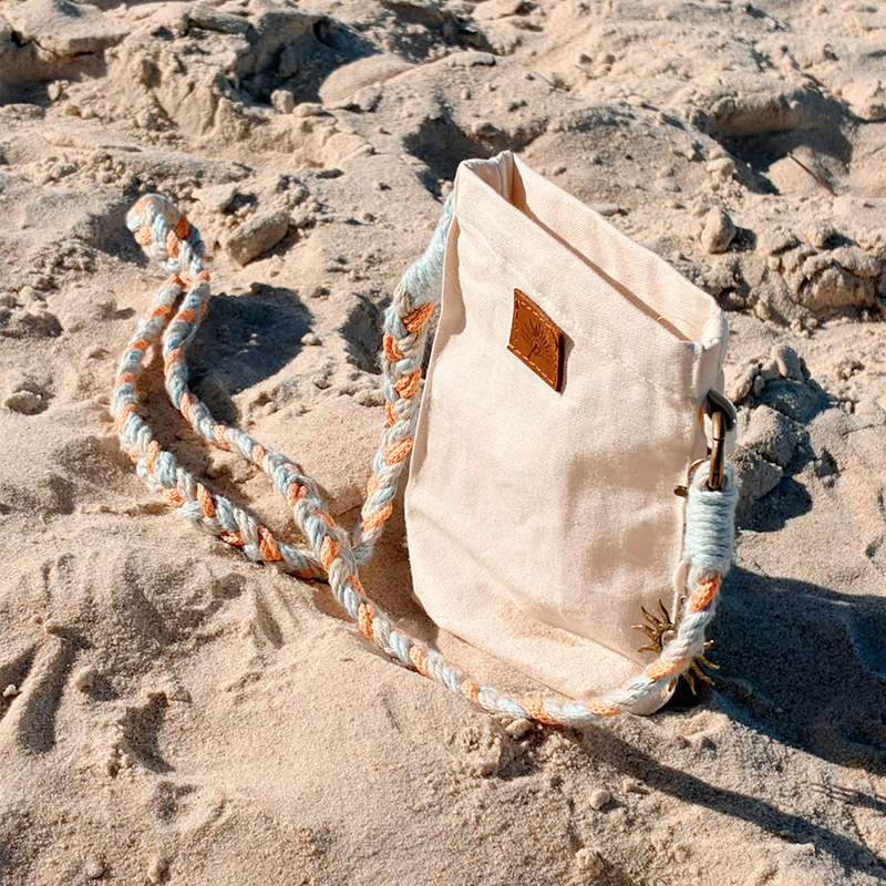 Bolsa Sol clara com alça trançada fotografada na praia