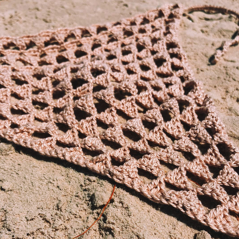 Bandana artesanal em crochê no tom areia, com trama vazada e delicada.