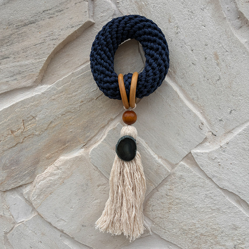 Elemento decorativo azul com argolas, pedra escura e franja clara
